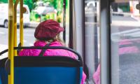 Kvinde med pink jakke sidder i bus